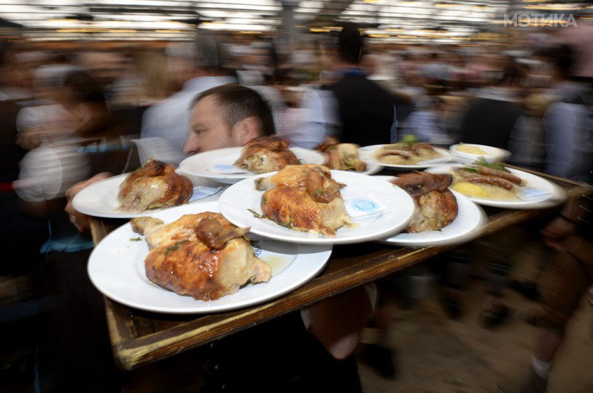 A waiter carries a tray of roast chicken during opening day of the 181st Oktoberfest in Munich