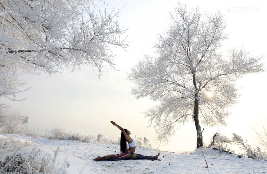 Xie Xiaoming, 26-year-old owner of a yoga club, practices yoga in thin clothes near trees covered by frosty fog on the snow-covered banks of Songhua River in Jilin