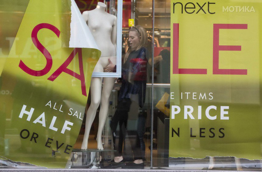 A shop assistant creates a window display in a Next store in central London