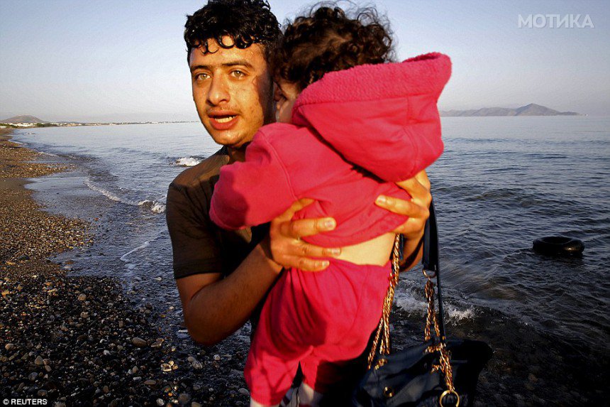 29150B7F00000578-3097559-A_Syrian_refugee_carries_a_toddler_off_a_dinghy_on_the_island_of-a-2_1432660184434