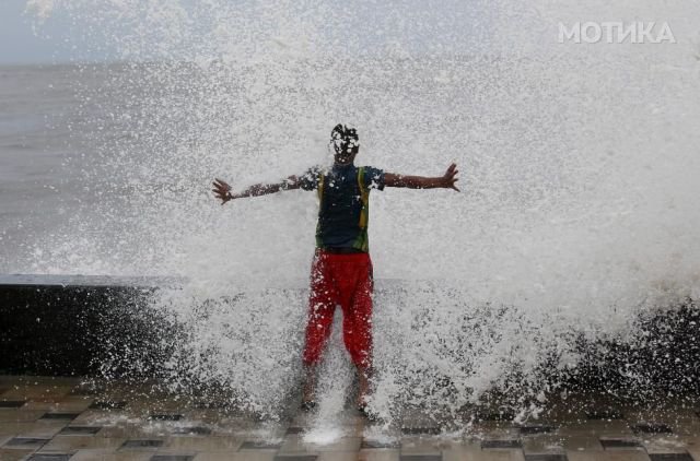 A boy gets drenched in a large wave during high tide at a sea front in Mumbai