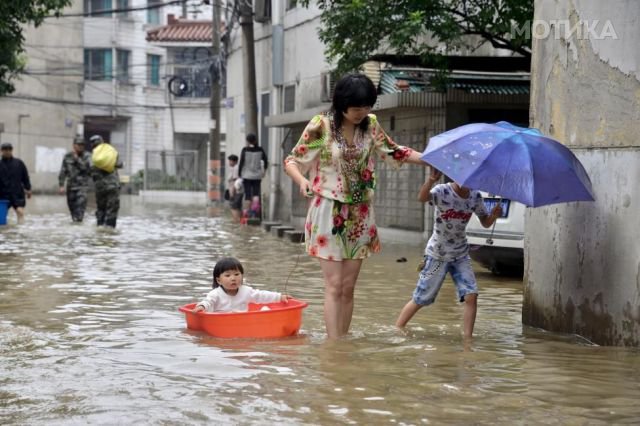 A woman with children wades through a flooded street after a heavy rainfall in Changzhou