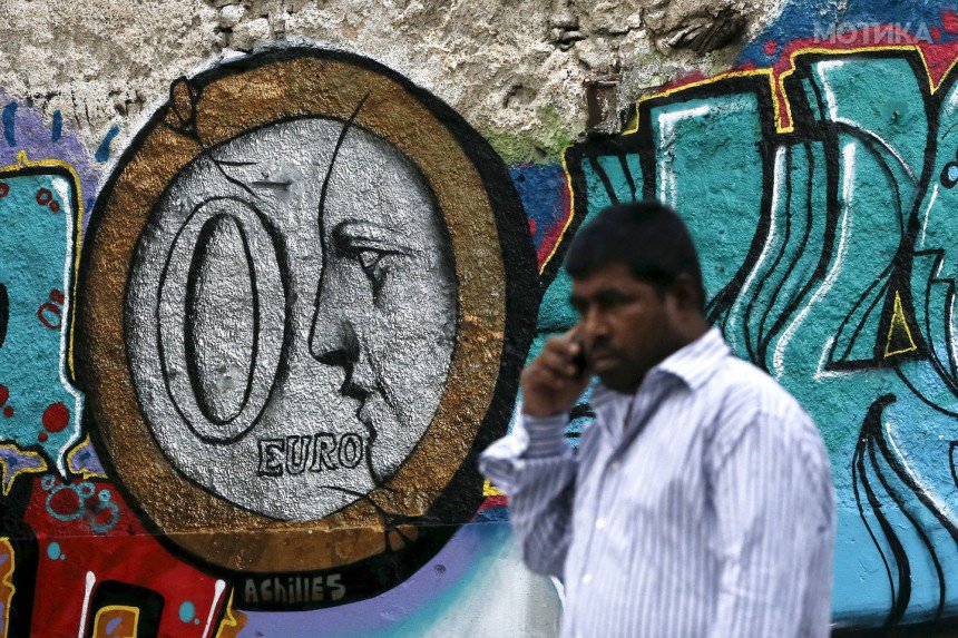 A man walks past a graffiti by Greek street artist Achilles, depicting a zero Euro coin in Athens