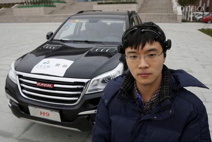 Researcher Zhang Zhao wearing a brain signal-reading equipment poses with a vehicle which can be controlled with his brain wave, during a demonstration at Nankai University in Tianjin