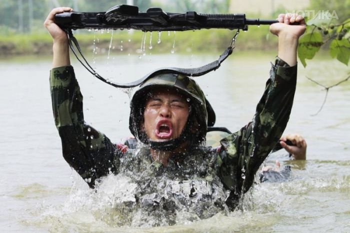 A paramilitary policeman raises up his gun and takes a breath while crossing a river during anti-terrorism drill in Hangzhou