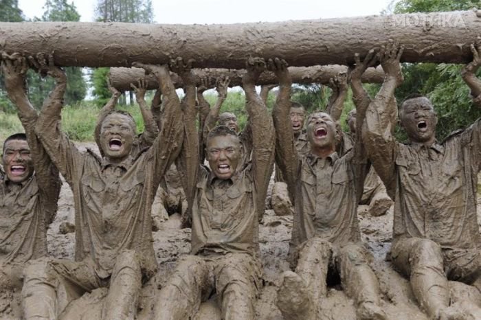 Paramilitary soldiers lift logs during physical training in mud in Chuzhou