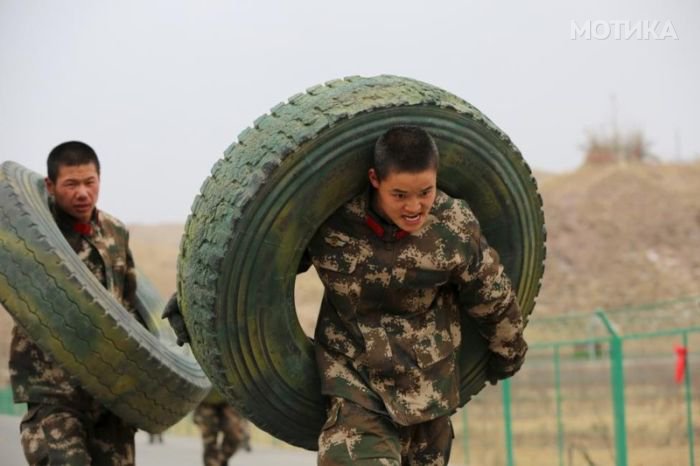 Paramilitary policemen carry tyres as they take part in a training session in Zhangye