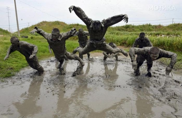 Paramilitary policemen jump during a training session in muddy water at a military base in Chuzhou